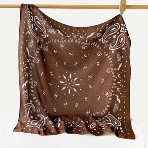 Detailed close-up showing the soft drape and paisley patterns of the large brown silk scarf