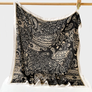 Détail d'un foulard en soie à motif chevrons et imprimé paisley sur tige en bois
