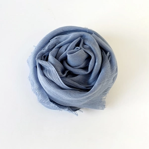 Detail of light blue cotton linen scarf showing soft texture and raw fringe edges
