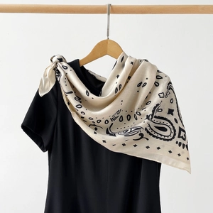 Detail of premium paisley silk scarf with black floral patterns on off-white fabric