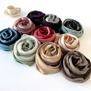 Solid color silk shawls and scarves displayed in various colors with a soft glossy texture