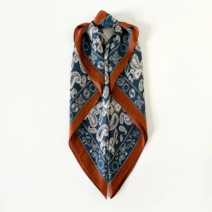 Dettaglio di sciarpa in seta paisley blu navy con bordi rosso ruggine e stelle