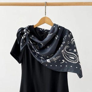 Detailed view of dark grey paisley satin scarf tied on a black top for a sleek look