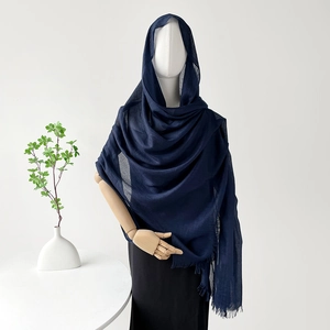 Vista detallada de un chal de algodón y lino azul oscuro con borlas en un maniquí