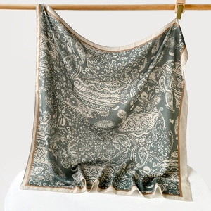 Vue détaillée d'un foulard en soie vert foncé avec motif cachemire sur barre en bois