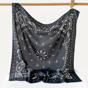Detail of navy blue paisley silk scarf draped on a wooden rod with gold clips