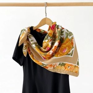 Detail view of a floral silk scarf with warm yellow and orange patterns on a black dress