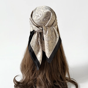 Elegante foulard in seta paisley con bordo nero indossato come fascia per capelli
