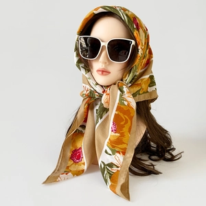 Detail of retro floral silk scarf styled as headscarf with orange flowers and sunglasses