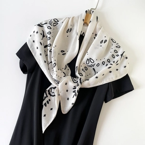 Detailed macro of a white paisley silk scarf with black floral patterns on a dark dress