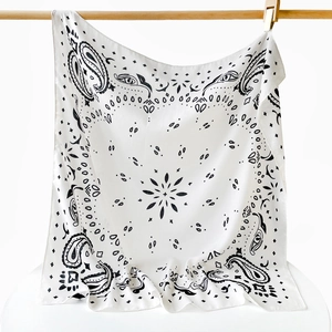 Detailed view of white silk scarf with black paisley and eye patterns on wooden stand