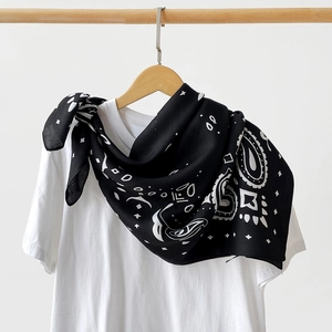 Detail of a black and white paisley silk scarf styled as a knot on a white t-shirt