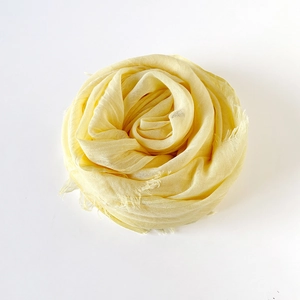 Macro detail of pale yellow cotton linen scarf showing natural fringe and crinkle texture