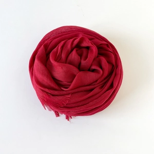 Detail of red cotton linen scarf with fine fringe trim folded into a rose flower shape