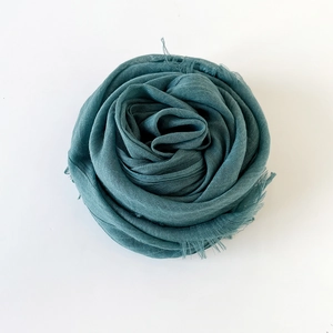 Detail of teal cotton linen scarf featuring a natural fringed edge and woven texture