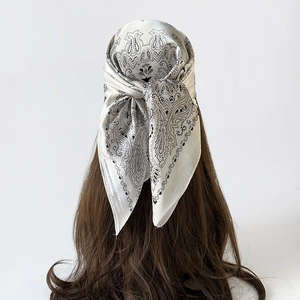 Detail van een zijden sjaal met paisley-motief geknoopt als een stijlvolle haarband