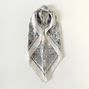 Detailopname van een zijdeachtige paisley vierkante sjaal met ivoorkleurige basis en zwart