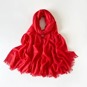 Detalle del pañuelo de algodón rojo con textura plisada y bordes de flecos finos