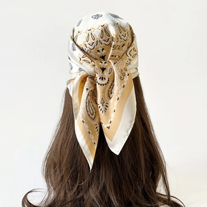Detailed back view of a satin headscarf tied as a headband with golden paisley patterns