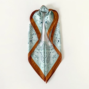 Detail of mint green paisley satin scarf with caramel brown border and knotted draping