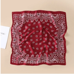 Detail van een donkerrode vierkante sjaal met witte paisley-patronen en zijdezachte textuur