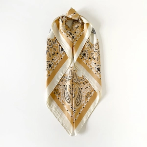 Detailed close-up of premium satin square scarf featuring elegant yellow paisley print
