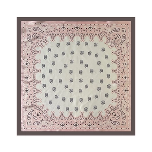 Detailed flat lay of a square silk scarf with light pink paisley patterns and fine texture