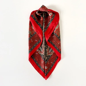 Detailed view of red paisley satin scarf with vintage ethnic patterns and silky texture