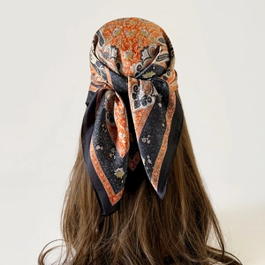 Close-up of vintage orange and black paisley silk square scarf worn as a stylish headscarf