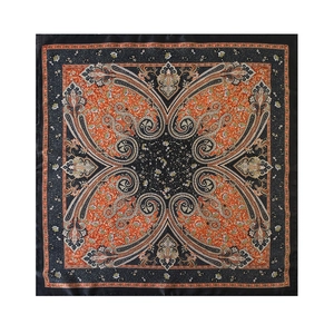 Detailed macro view of smooth satin paisley square scarf with vibrant orange and black patterns