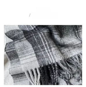 Detailed macro view of grey checkered cashmere-feel fabric and soft fringe edging