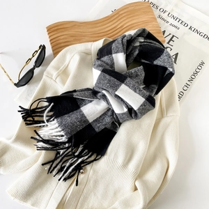 Close-up of classic black and white plaid scarf with fringe details and soft wool texture