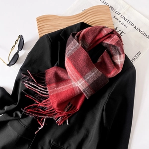 Detailed view of classic red plaid scarf with fine fringes on high-quality cashmere fabric