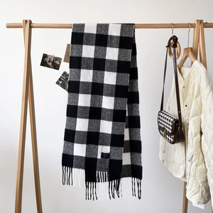 Detail of classic black and white buffalo plaid scarf with fringes and woven fabric label