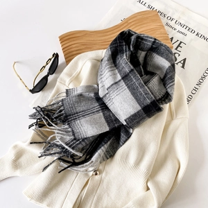 Detailed view of black and white plaid scarf with fringe on a white aesthetic background