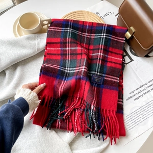 Detailed close-up of a warm red plaid scarf with fringes and soft woven fabric texture