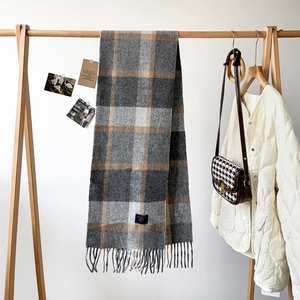 Detail of grey plaid cashmere scarf showing soft fringe and 100% blend woven label