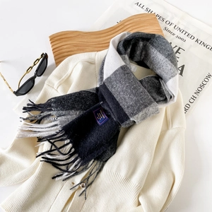 Detailed view of black and white plaid cashmere scarf with fringes and woven label