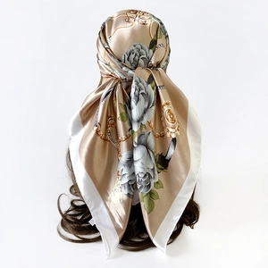 Detail van champagne goud satijnen sjaal met grijs-blauwe rozenprint gedragen als hoofddoek