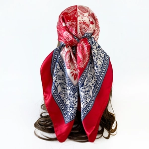 Detail view of red and blue paisley print silk scarf worn as a stylish headband on hair