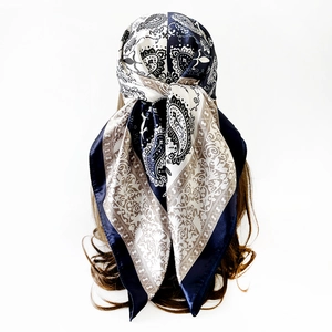 Detailed close-up of navy and beige paisley pattern on a silky square headscarf for women