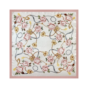 Detail van satijnen sjaal met roze rozen, gouden kettingen en parelmotieven