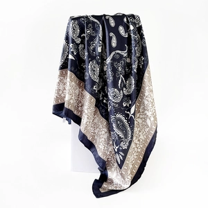 Detail of navy silk scarf featuring elegant paisley patterns and golden border details