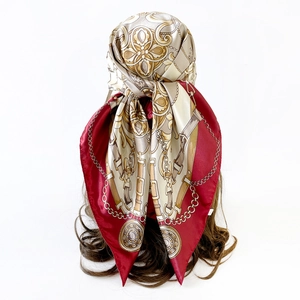 Detail of red and gold baroque chain print satin scarf tied as a headwrap on model