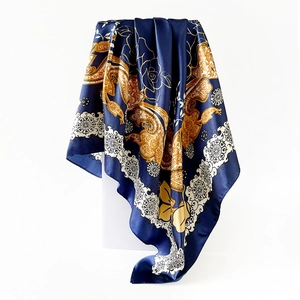 Detailed view of luxury navy satin scarf with golden paisley pattern on white stand