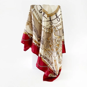 Detail of satin silk scarf featuring luxury gold chain print and burgundy borders