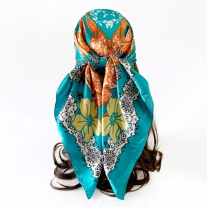 Detailed close-up of peacock blue satin scarf with vintage ethnic pattern on silk texture