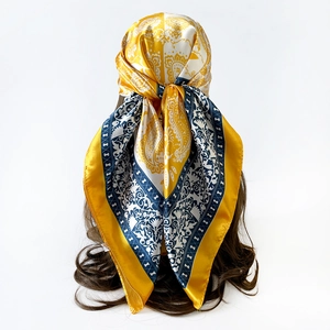Macro detail of yellow and blue Paisley silk square scarf styled as a headscarf wrap