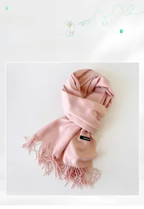 Close-up of a pink imitation cashmere scarf featuring delicate fringe and a black label