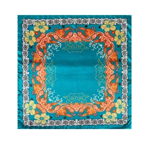 Detailed flat lay of a satin square scarf featuring orange paisley and floral print